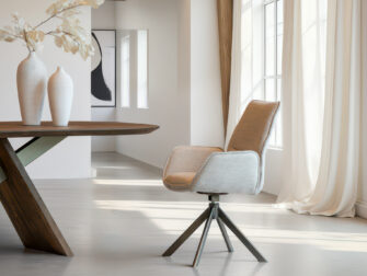 Tijdloze eetkamerstoel met conische metalen poten en een gladde zitting in lichte crème tint met zachte structuur