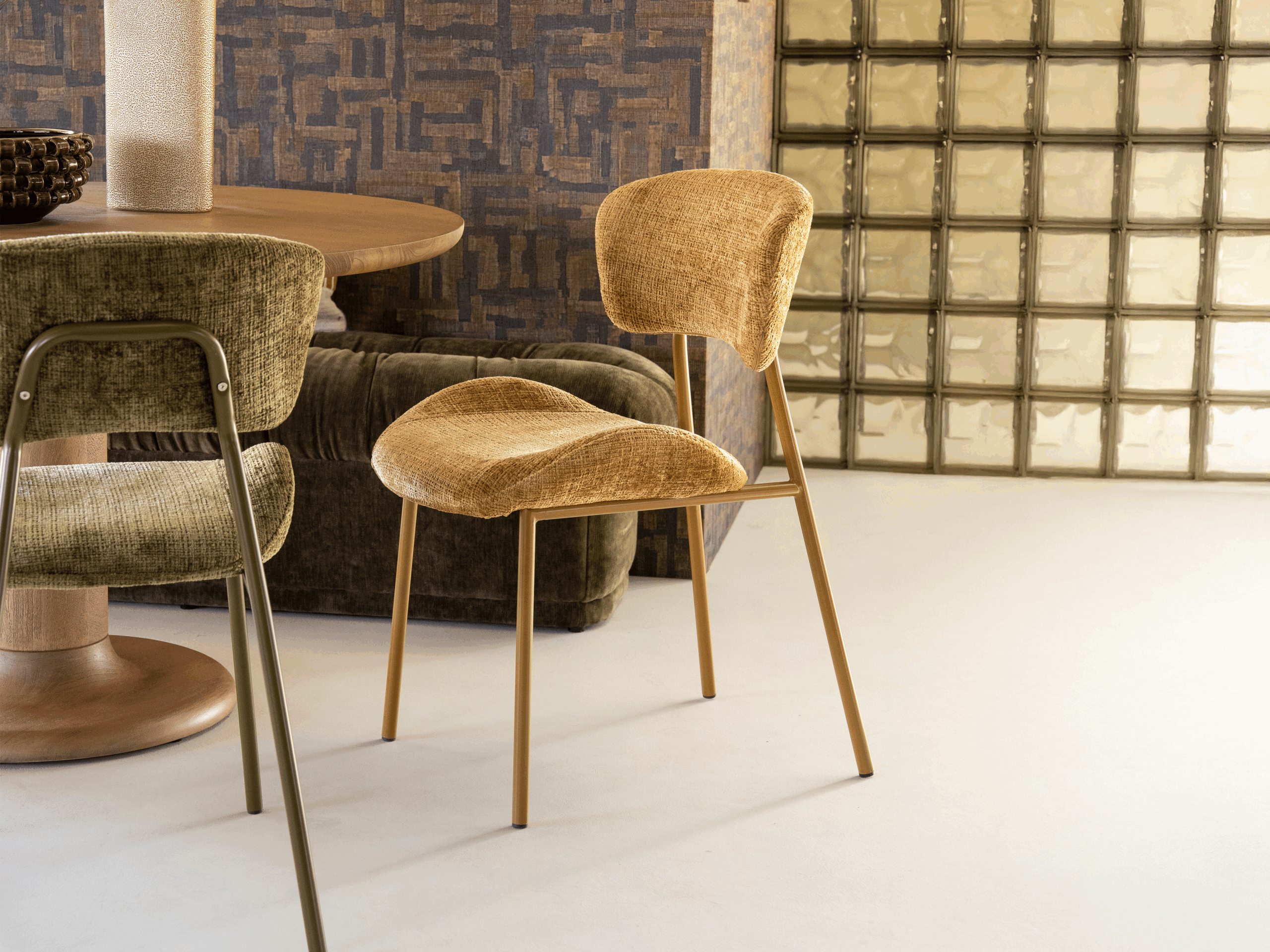 Eetkamerstoel met zachte kuipvormige zitting en subtiel gebogen rugpaneel op metalen poten