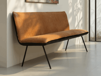 Elegante eetkamerbank met cognackleurige bekleding en slanke zwarte poten