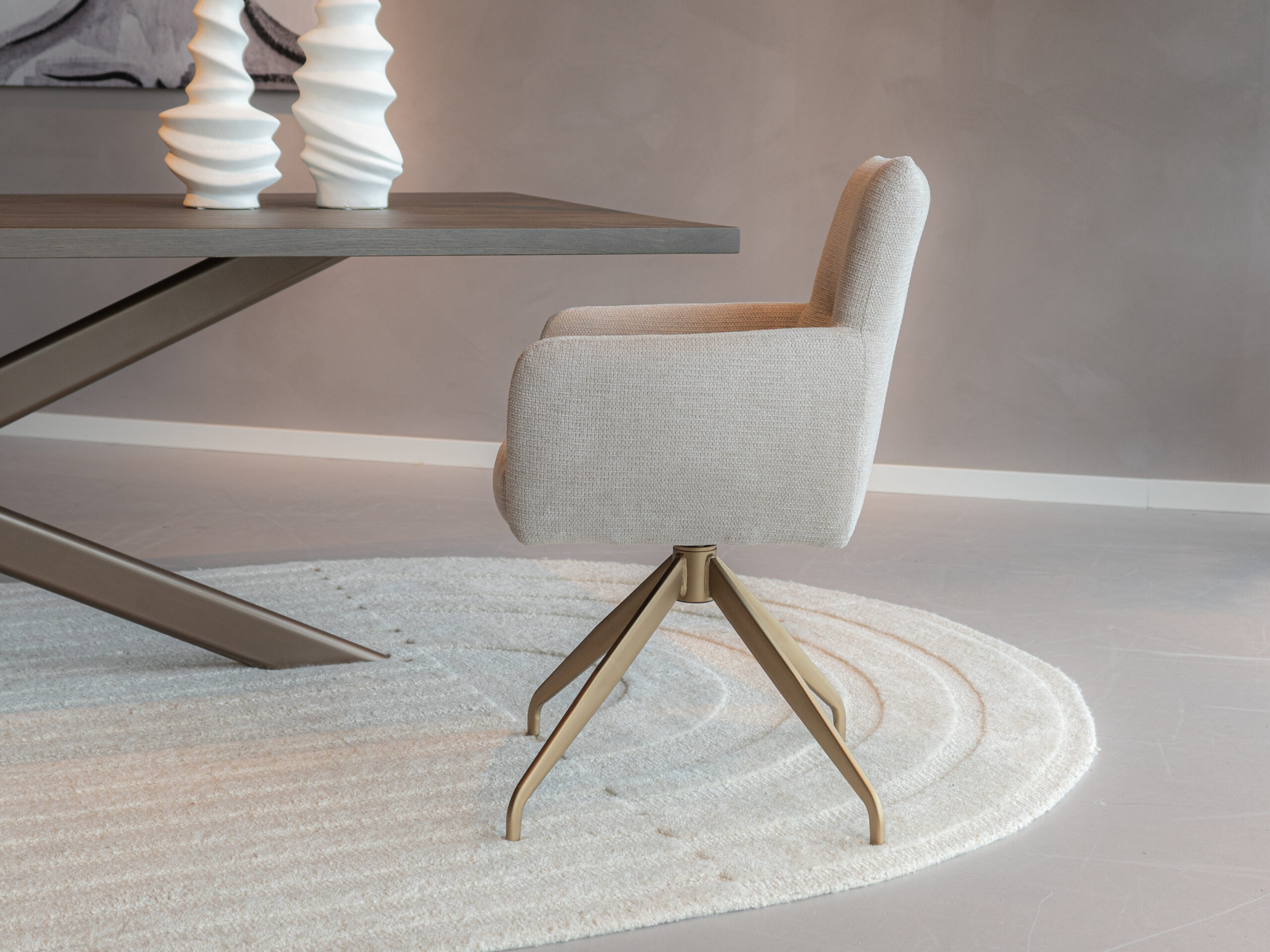 Stoffen kuipstoel in beige tint met bronzen poot