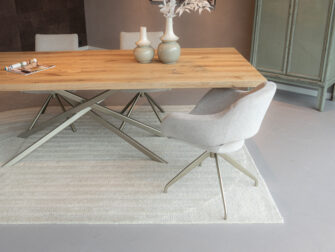 Ronde eetkamerstoel in zachte beige stof met smalle champagne draaipoot