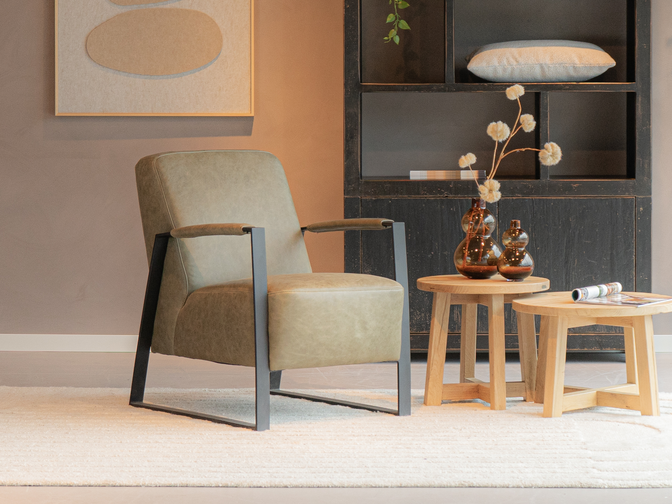 Olijfgroene fauteuil met een zwarte beugelpoot en armleuningen